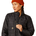 Person wearing a black puffer jacket and orange beanie on a white background