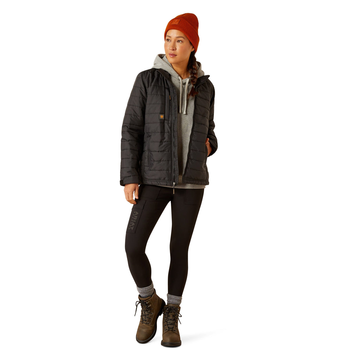 Person wearing a dark jacket, leggings, and boots on a white background