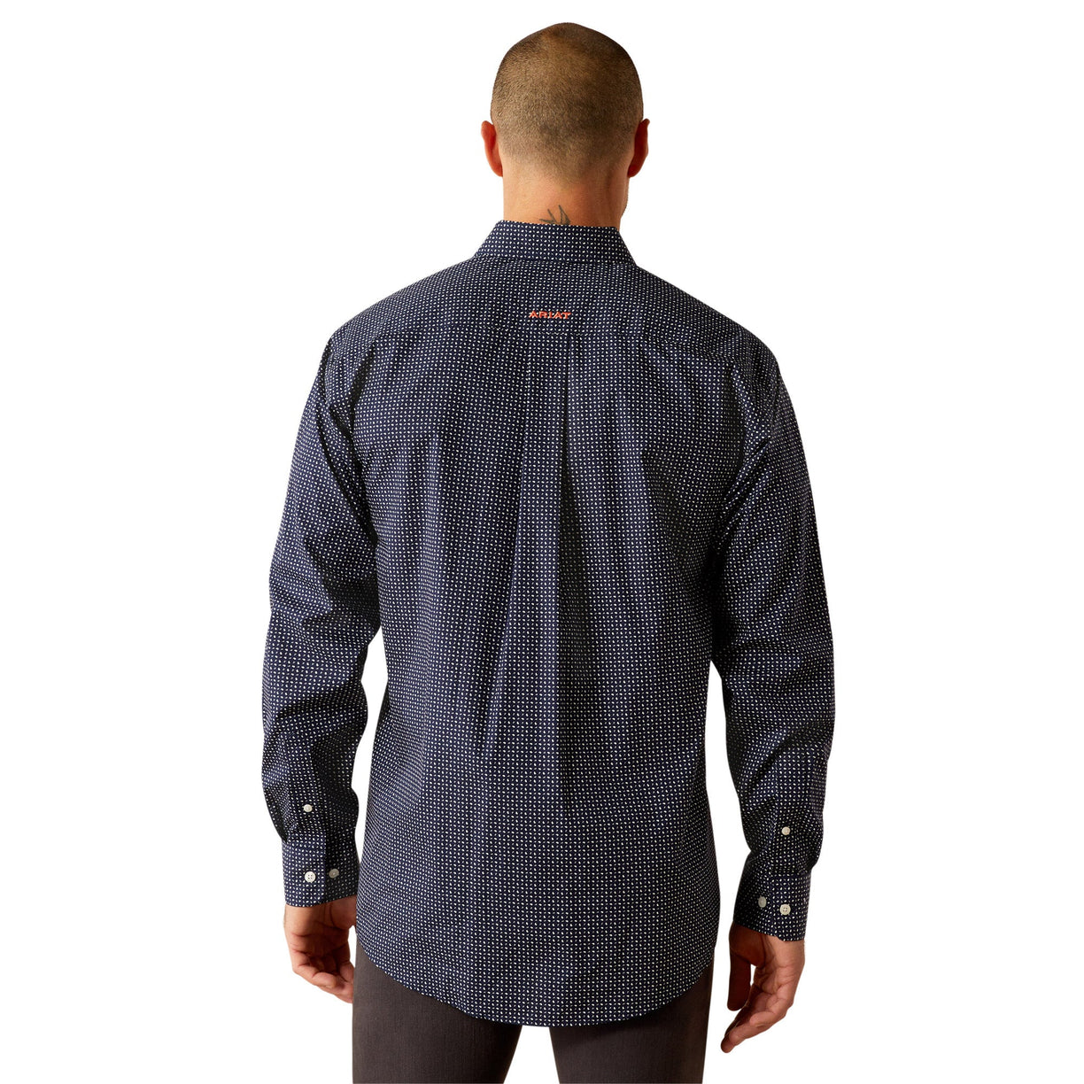 Man wearing a patterned dark shirt and dark pants on a white background