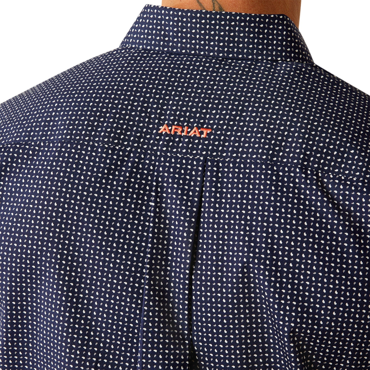 Man wearing a patterned dark shirt and dark pants on a white background