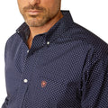 Man wearing a patterned dark shirt and dark pants on a white background