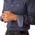 Man wearing a patterned dark shirt and dark pants on a white background
