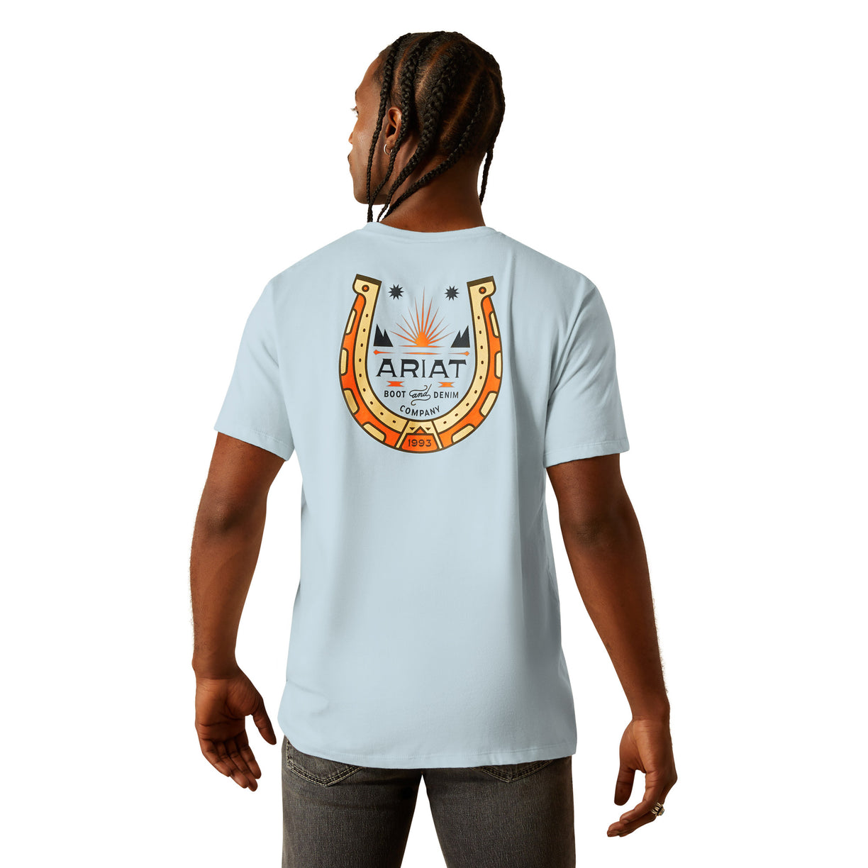 Person wearing a light blue t-shirt with an Ariat logo on the back, standing against a white background.