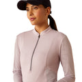 Woman wearing a light pink long-sleeve athletic top with a zipper on a white background