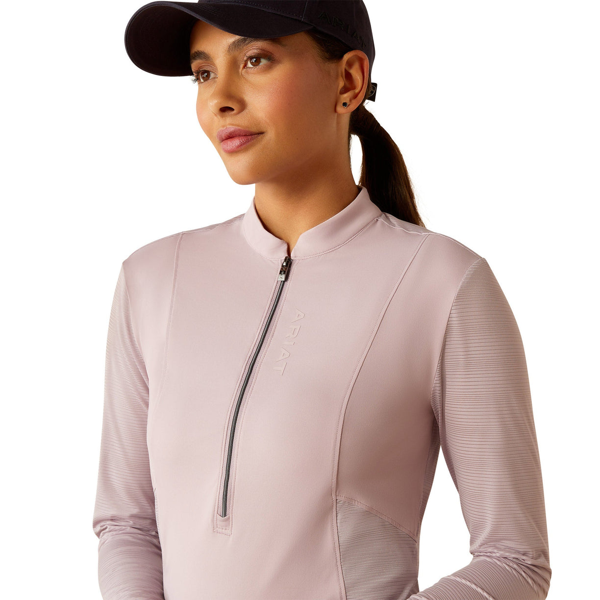 Woman wearing a light pink long-sleeve athletic top with a zipper on a white background