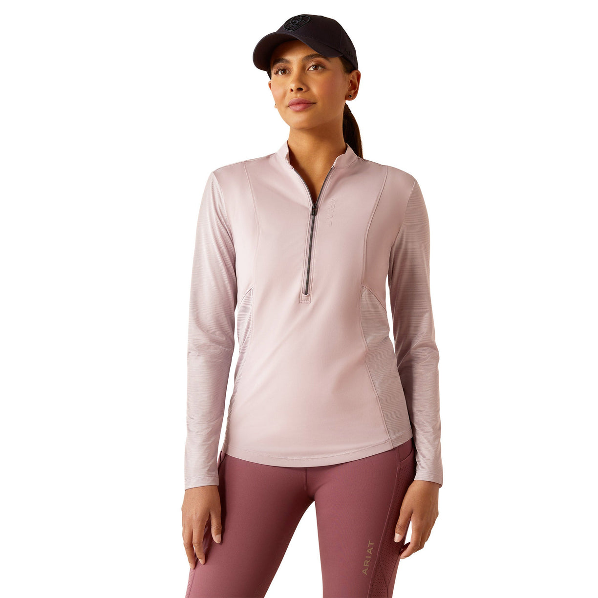 Woman wearing a light pink long-sleeve athletic top and maroon leggings on a white background
