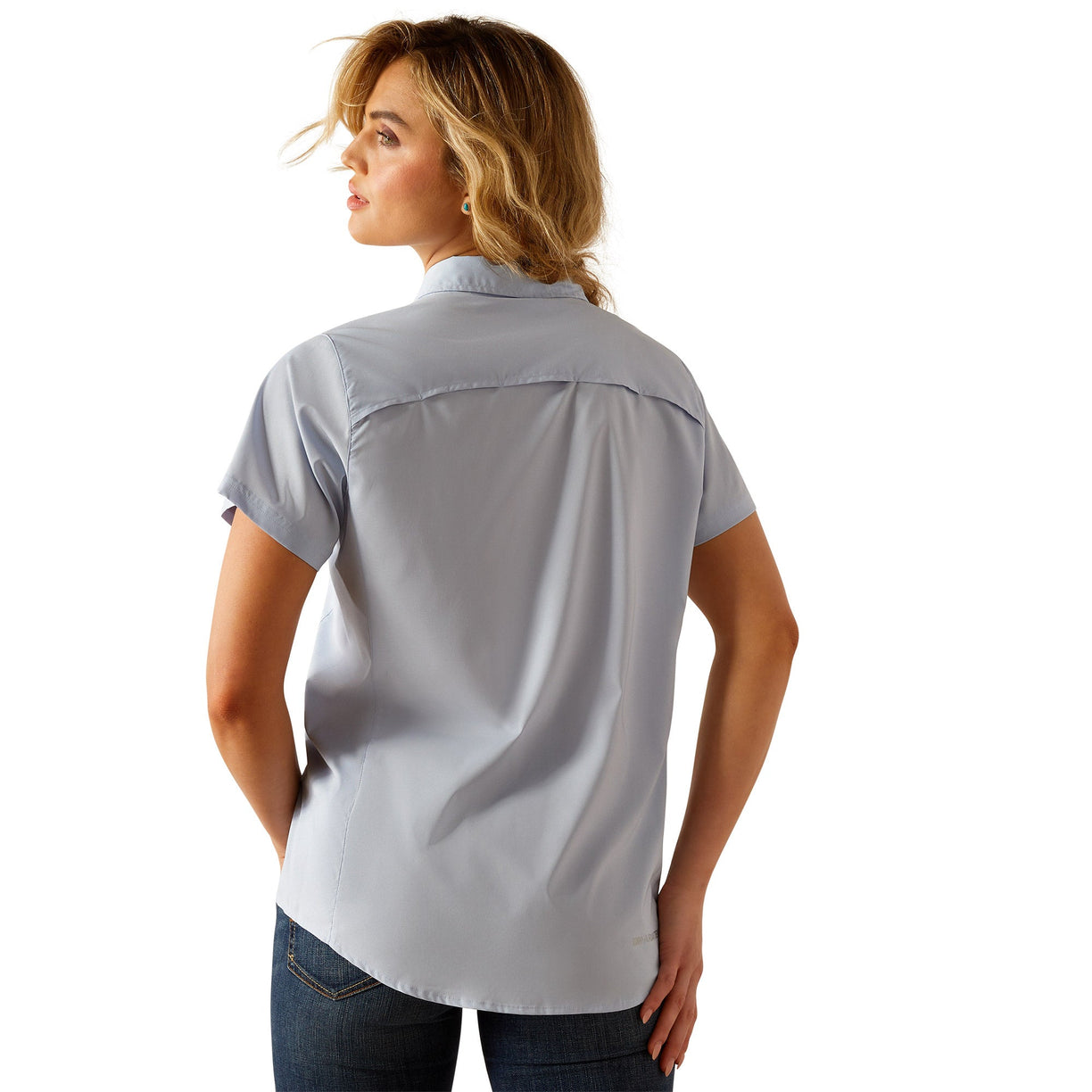 Woman wearing a light blue button-up shirt, jeans on a white background