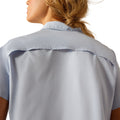 Woman wearing a light blue button-up shirt, jeans on a white background