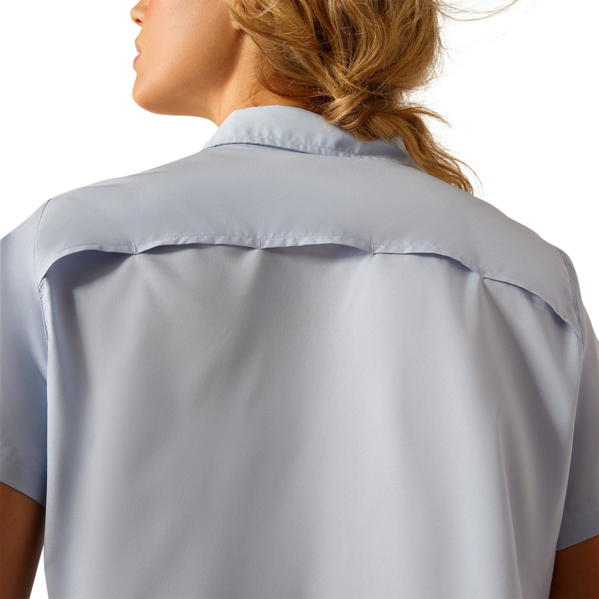 Woman wearing a light blue button-up shirt, jeans on a white background