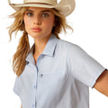 Woman wearing a light blue button-up shirt, jeans on a white background