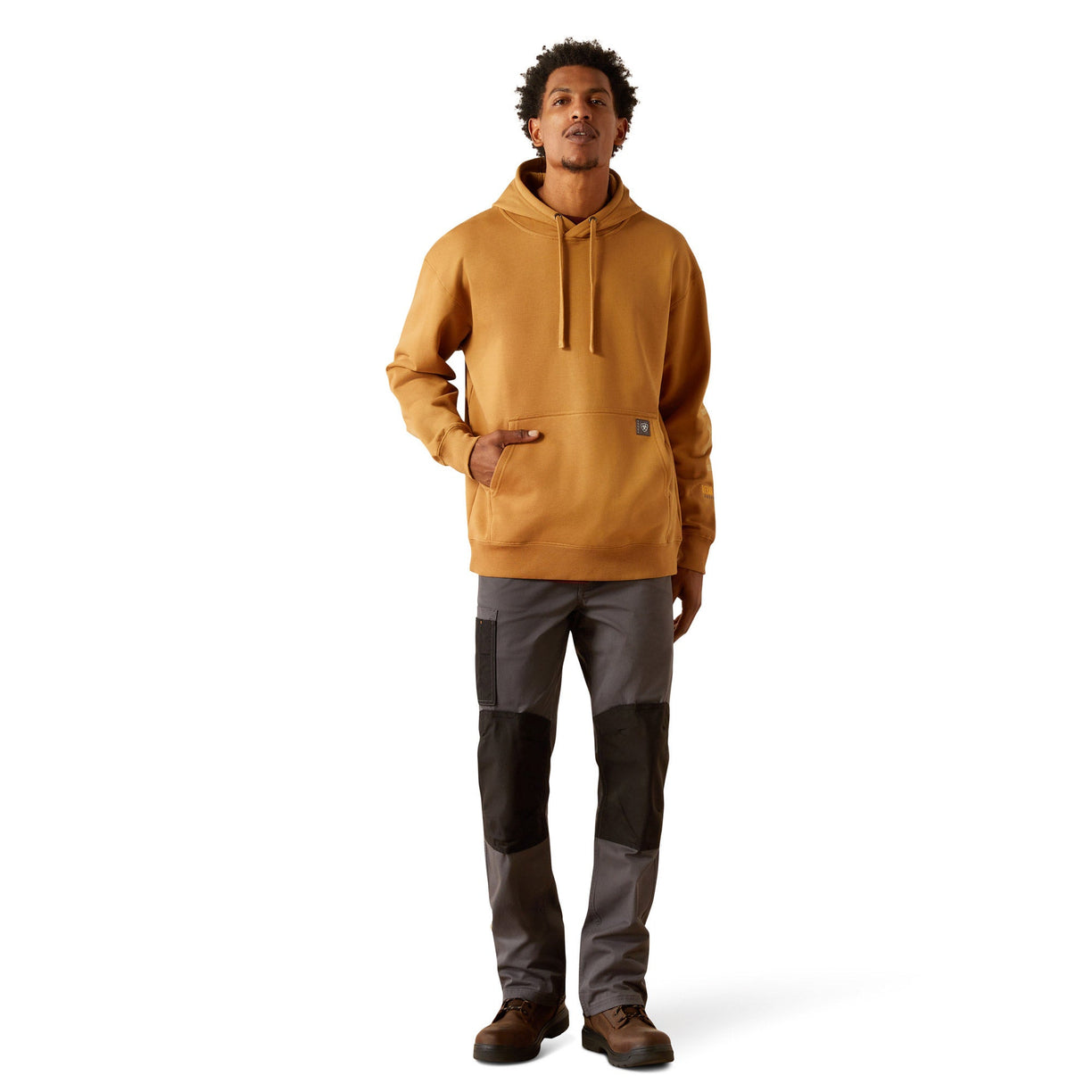 Man wearing a mustard yellow hoodie with Ariat branding on a white background