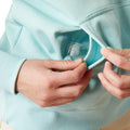 Person wearing a light blue hoodie with 'Ariat' branding on a white background