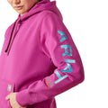 Person wearing a pink hoodie with Ariat brand logo on a white background