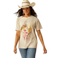 Woman wearing a beige t-shirt with floral and deer design, blue jeans, and a cowboy hat on a white background