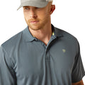 Man wearing a blue gray polo shirt with Ariat branding and cap on a white background