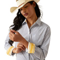 Woman wearing a patterned shirt, jeans, and a cowboy hat on a white background
