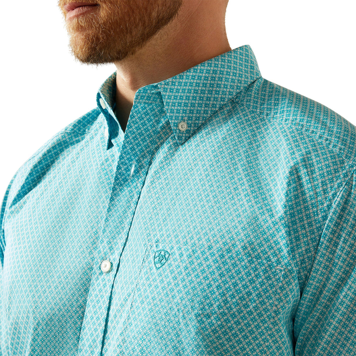 Close-up of a person wearing a turquoise patterned shirt with a brand logo.