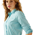 Woman wearing a blue checkered shirt with a visible brand logo on a white background