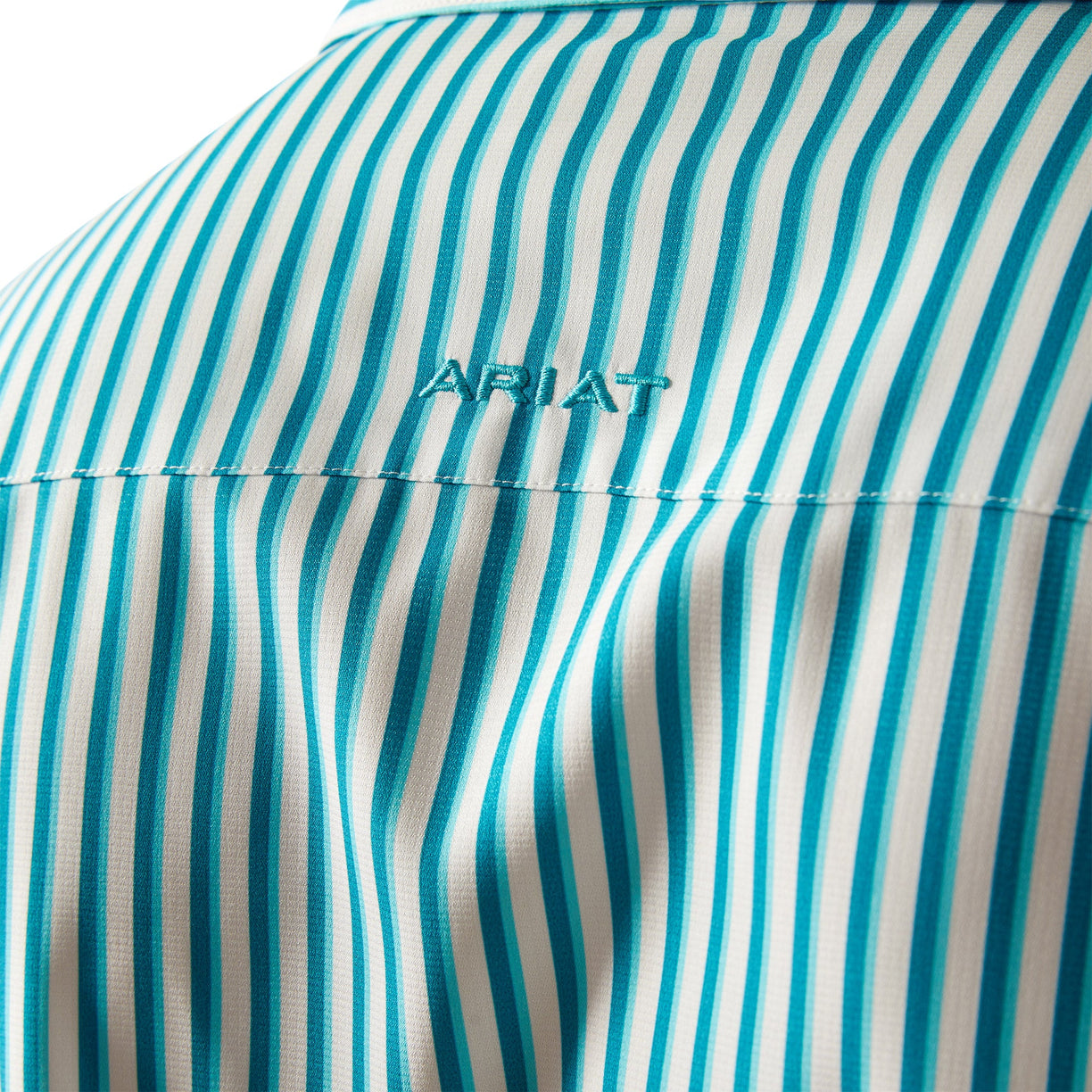 Close-up of a teal and white striped shirt with 'Ariat' branding.