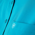 Close-up of a blue shirt with a logo on the chest pocket.