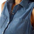 Woman wearing a blue sleeveless denim top and light blue denim on a white background