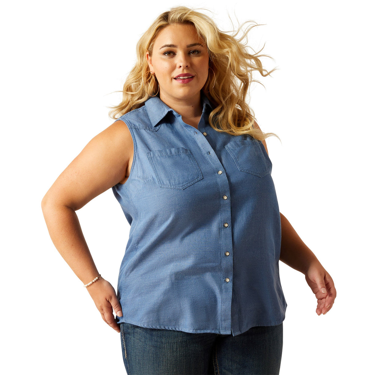 Woman wearing a blue sleeveless denim top and light blue denim on a white background