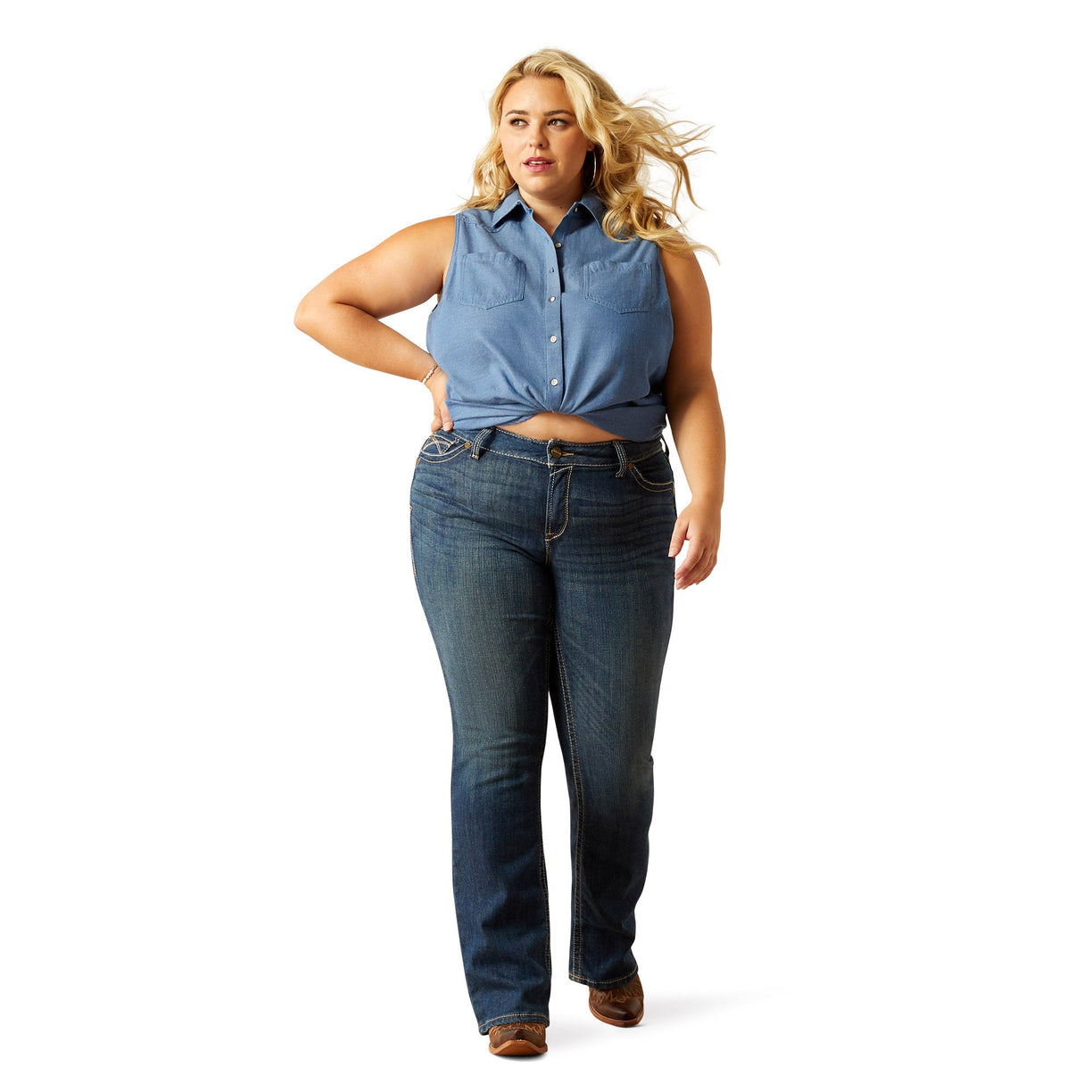 Woman wearing a blue sleeveless denim top and light blue denim on a white background