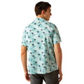 Man wearing a light blue shirt with palm tree pattern on a white background