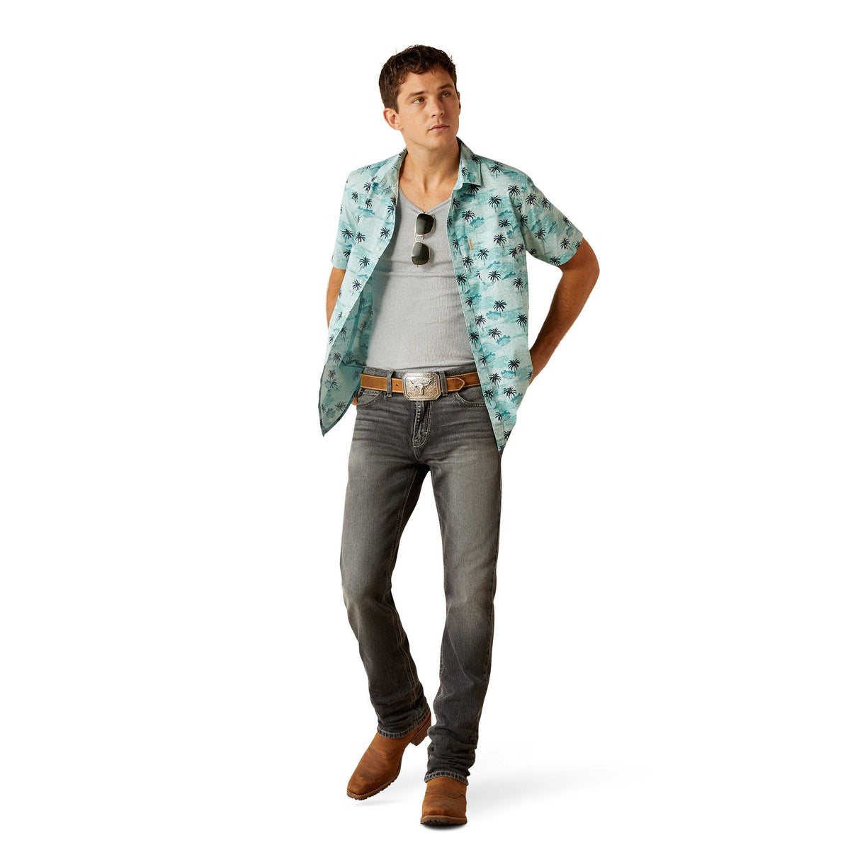 Man wearing a floral shirt, gray jeans, and brown boots on a white background