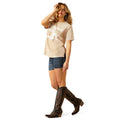 Woman wearing a beige t-shirt, denim shorts, and brown cowboy boots on a white background