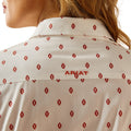 Close-up of a beige shirt with red pattern and 'Ariat' branding.