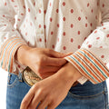 Close-up of a person wearing a patterned shirt with rolled-up sleeves and jeans, focusing on the waist area.