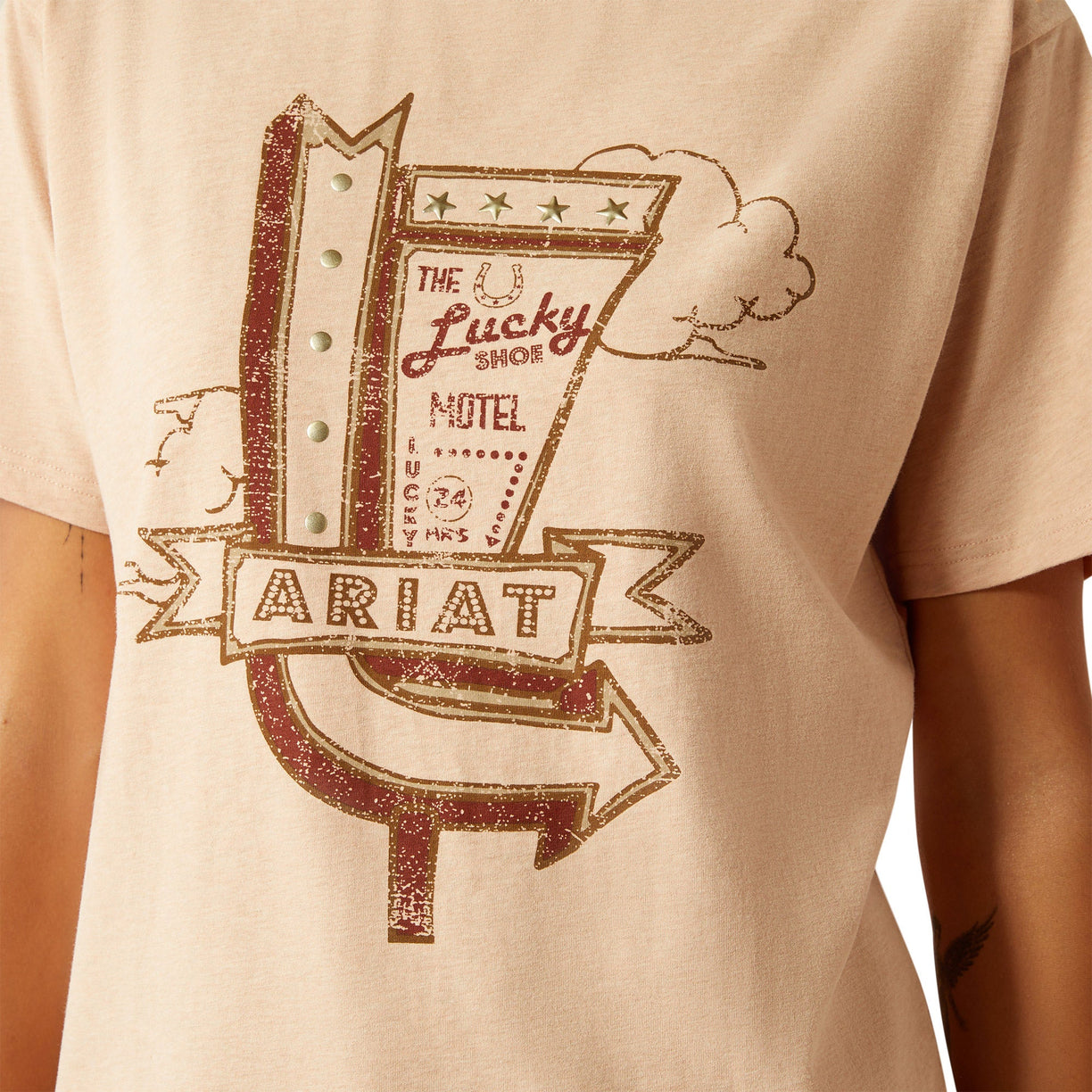 Beige t-shirt with 'Lucky Shoe Motel' graphic design on a person wearing it.