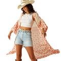 Woman wearing a floral kimono, white crop top, denim shorts, and cowboy hat on a white background