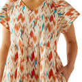 Woman wearing a colorful dress with orange, blue, and red patterns on a white background