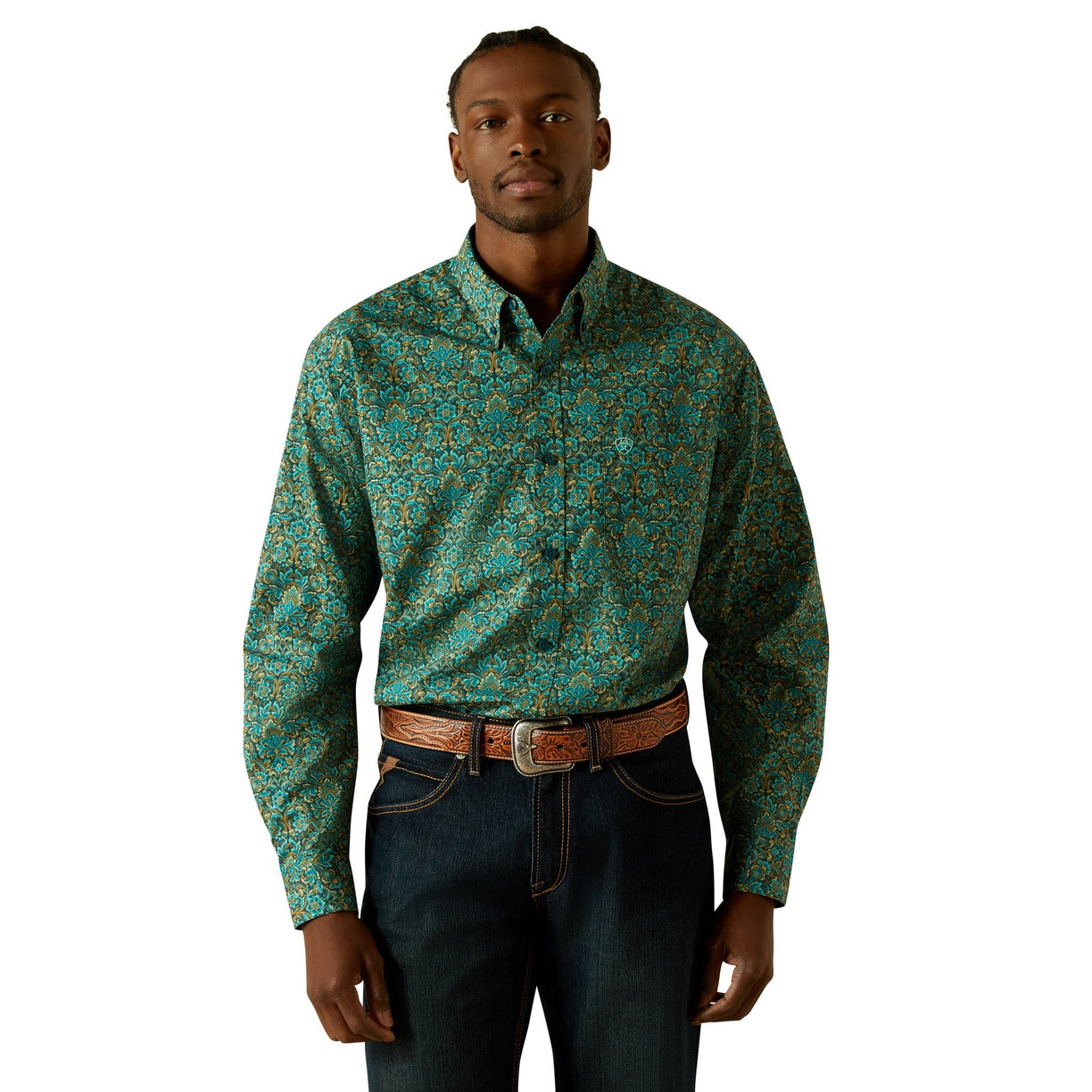 Man wearing a patterned teal shirt and dark jeans on a white background