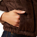 Close-up of a hand adjusting the waistband of a brown puffer jacket.
