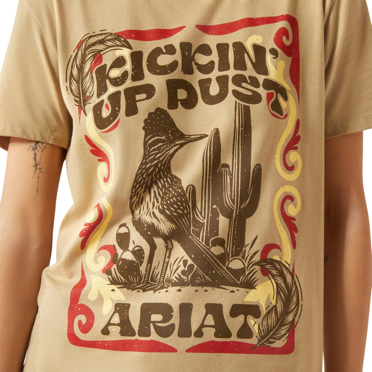 Beige t-shirt with 'Kicking Up Dust' and Ariat graphic design.