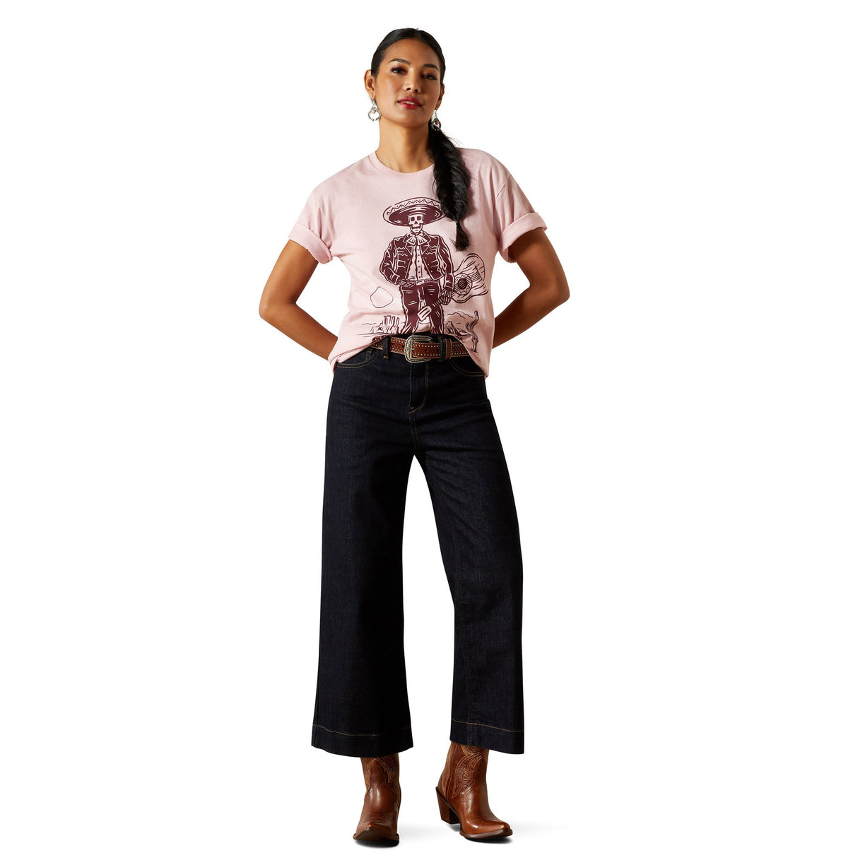 Woman wearing a pink t-shirt with a graphic design and dark jeans on a white background