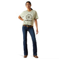 Woman wearing a light green Ariat t-shirt and blue jeans on a white background