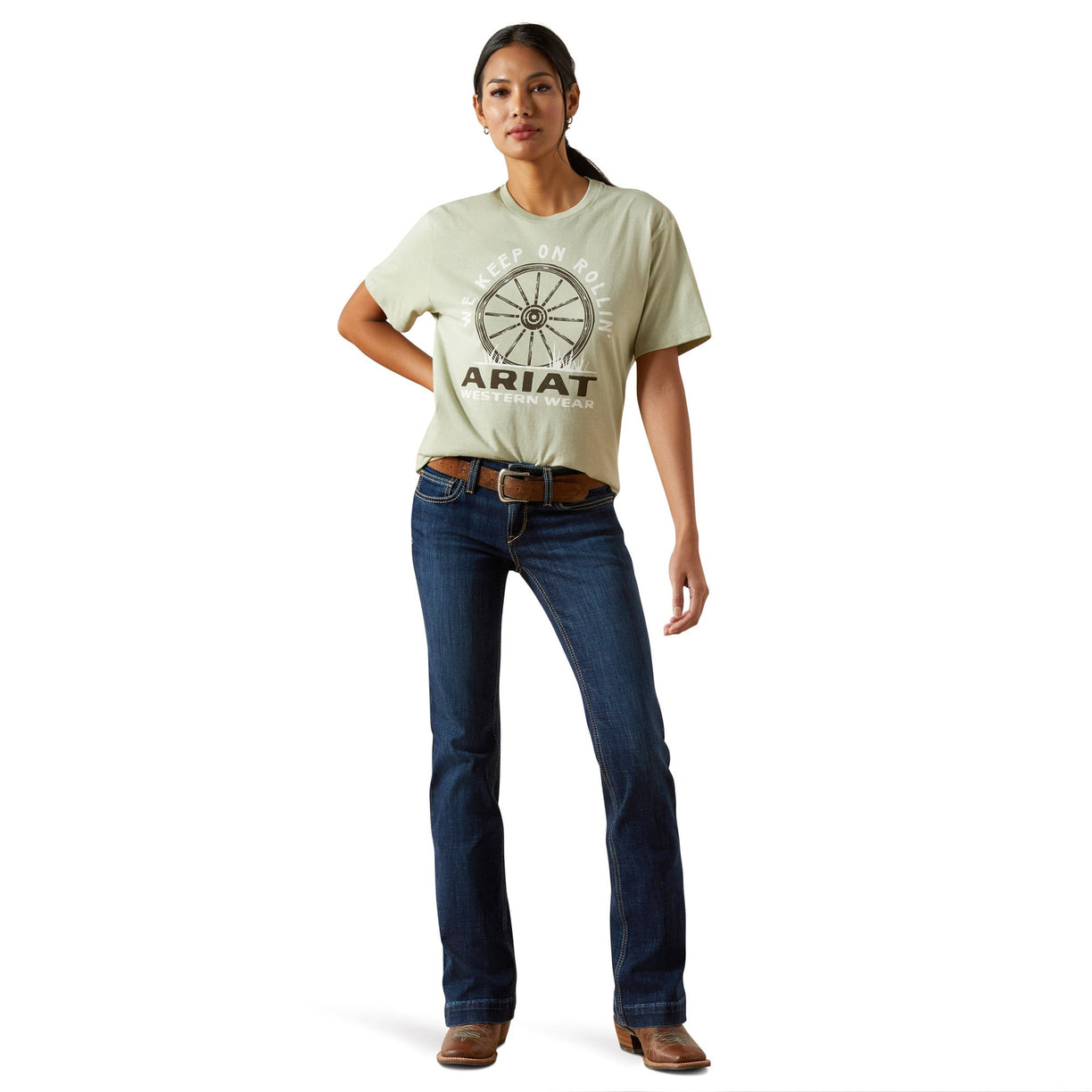 Woman wearing a light green Ariat t-shirt and blue jeans on a white background