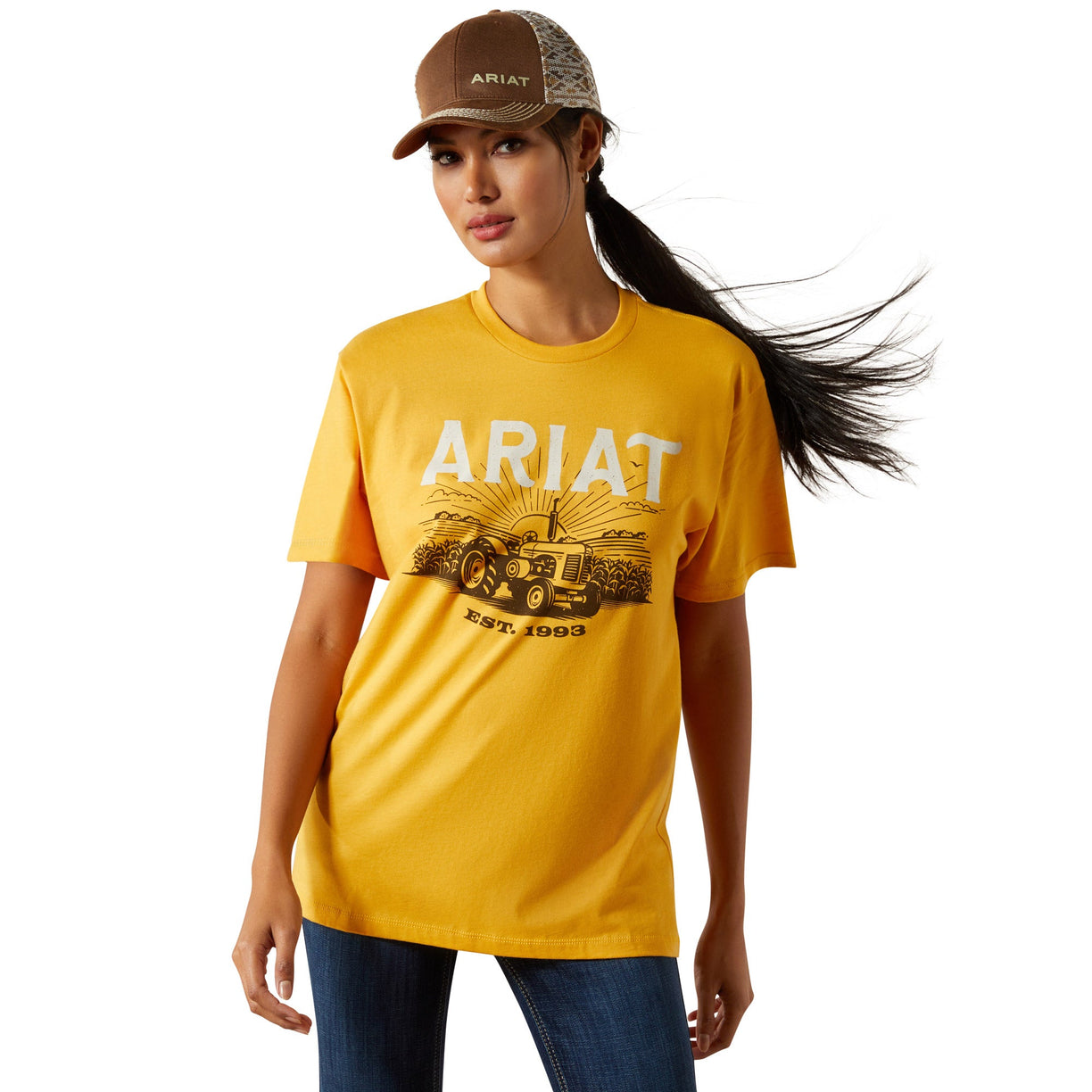 Woman wearing a yellow Ariat t-shirt and cap on a white background