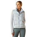 Woman wearing a light blue puffer vest over a white shirt on a white background