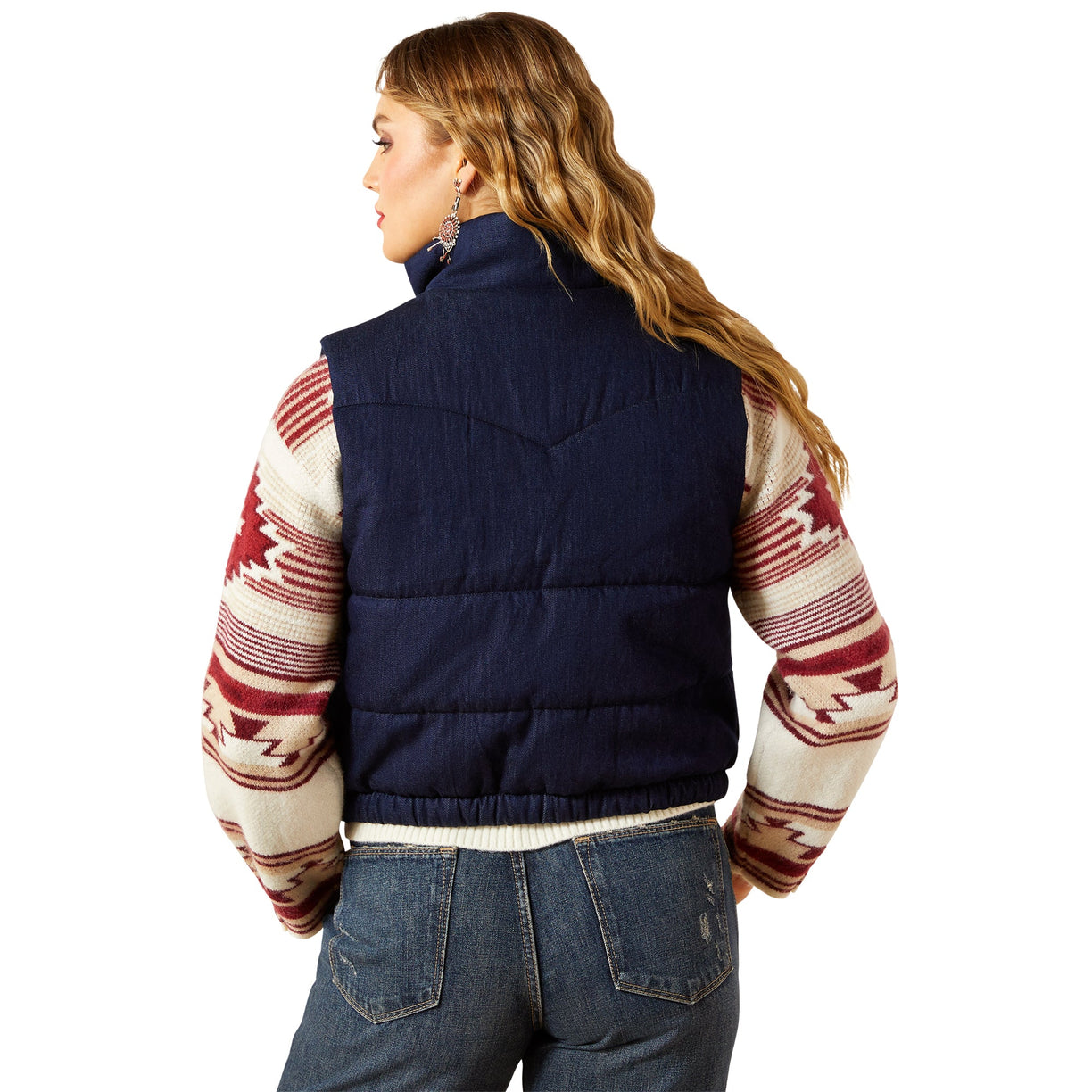 Person wearing a navy puffer vest over a patterned sweater on a white background