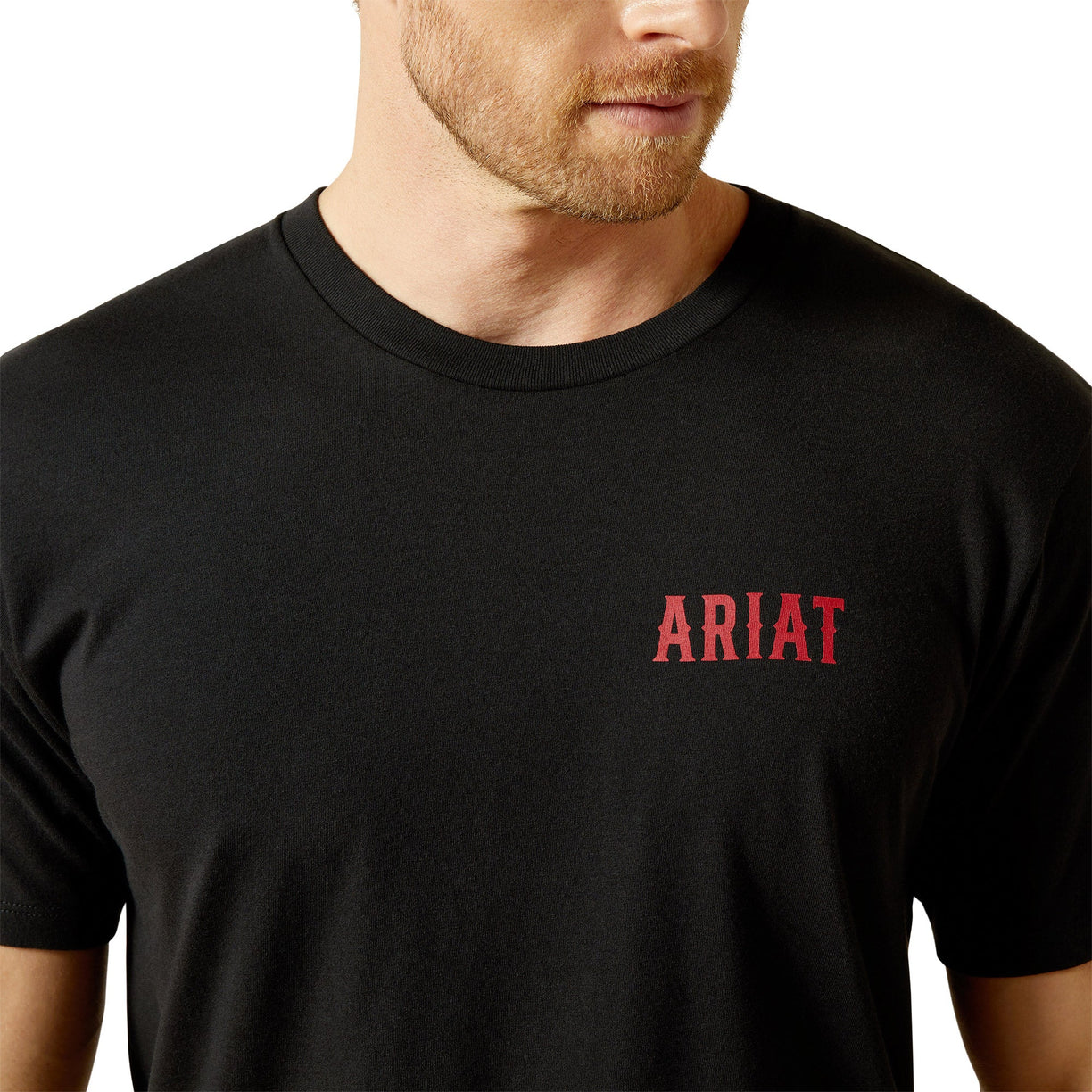 Black t-shirt with red 'ARIAT' logo worn by a person on a white background