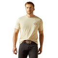 Man wearing a beige t-shirt with a logo and dark pants on a white background