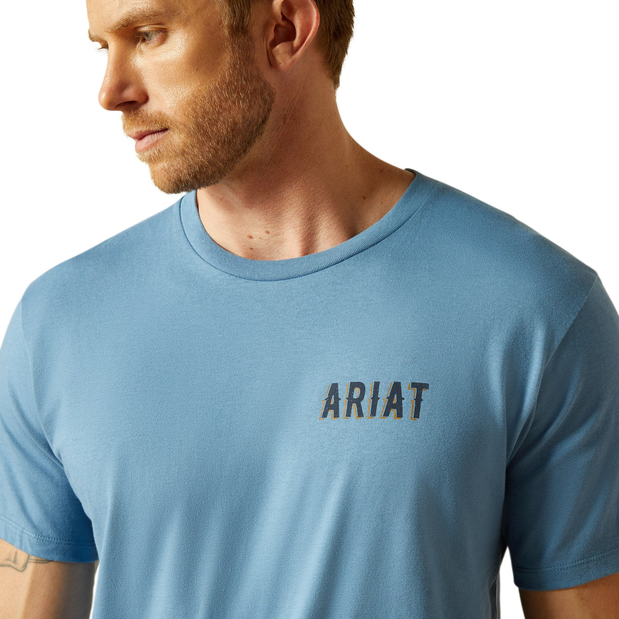 Man wearing a blue Ariat t-shirt on a plain background