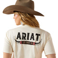 Person wearing a beige shirt with 'Ariat' branding and a brown cowboy hat on a white background