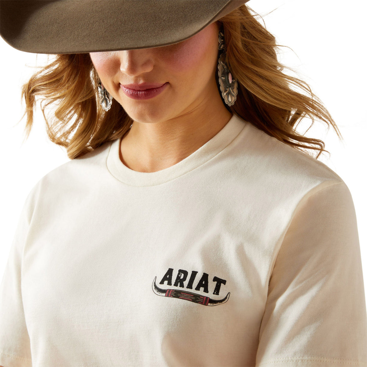 Woman wearing a white Ariat shirt with a beige hat on a white background