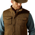 Man wearing a brown vest over a blue shirt with a white background